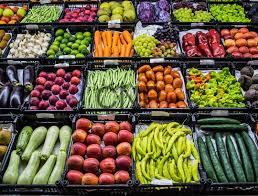 Assorted fresh fruits and vegetables displayed in market crates, organized in colorful rows.