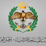 Logo of a government or military emblem: an eagle with outstretched wings, a gold crown above, green laurel wreaths on either side, crossed swords and an anchor beneath, with stylized Arabic text below.