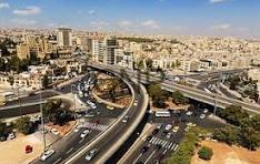 AMMMA - Center News Network Aerial view of a complex multi-level highway interchange weaving through a dense urban area with beige buildings under a blue sky.