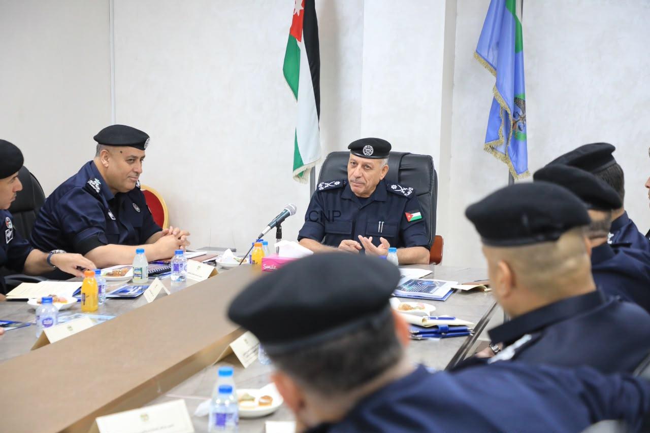 POJA - Center News Network Senior police officer in uniform seated at head of conference table, leading a formal meeting with colleagues, flags behind him.