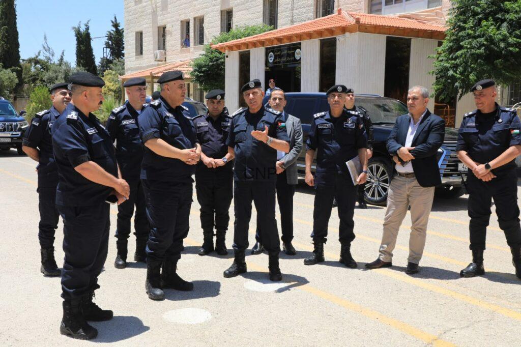 POJA2 - Center News Network Group of uniformed police officers listening as a speaker talks outdoors in a parking lot outside a building, with cars nearby.