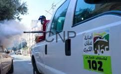 amameh - Center News Network White emergency vehicle with Arabic text and 102, a firefighter stands on its rear step as smoke billows nearby.
