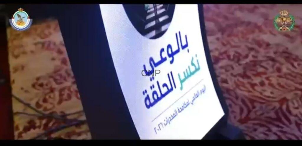 Standing banner on a patterned carpet with Arabic text and two emblems in the top corners, likely a conference or event poster.