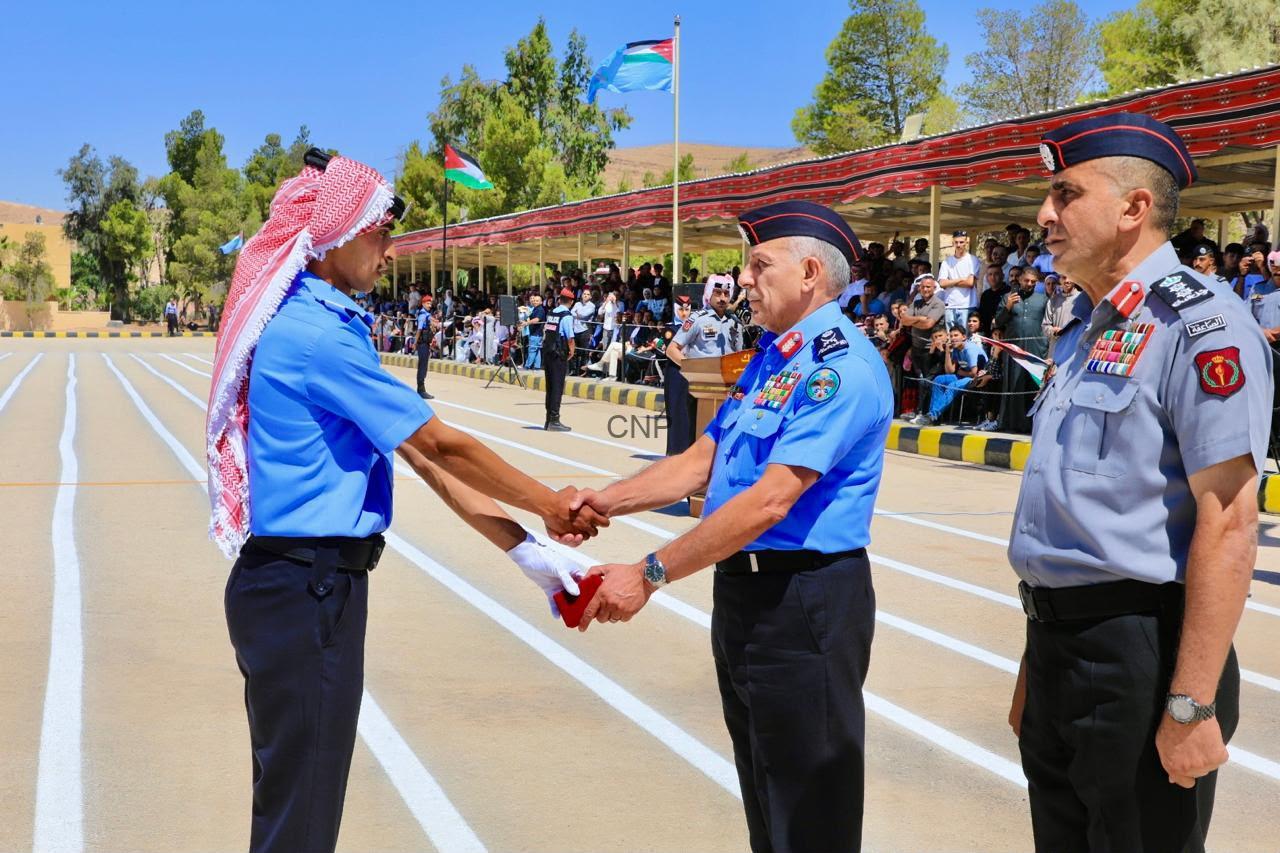 haf1 - Center News Network Two uniformed officers shake hands during a formal ceremony on a parade ground, with a crowd watching under a striped canopy and flags in the background.