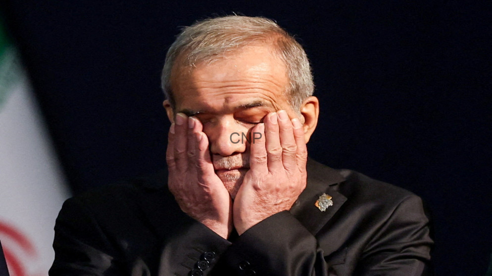 image - Center News Network Older man with gray hair holding his face in his hands on a dark stage, eyes closed in thought or fatigue.