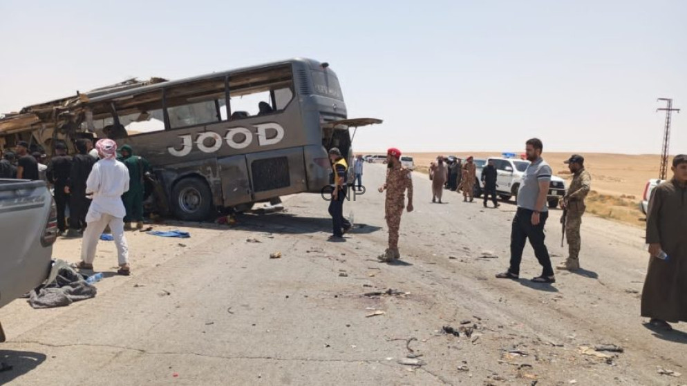 image - Center News Network Bus overturned on a desert highway after a crash; bystanders and security personnel assess the scene.