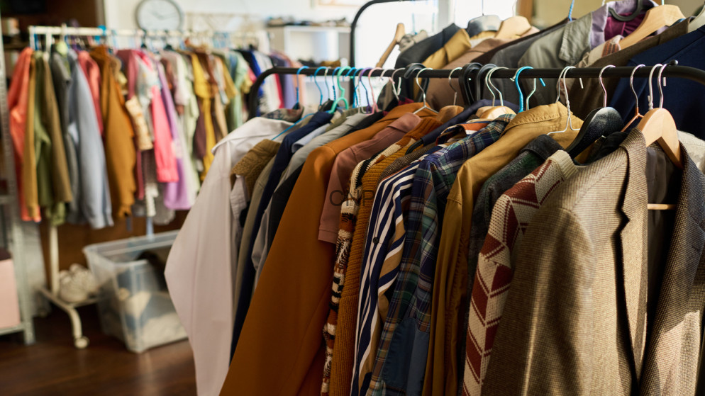 image - Center News Network Clothes on racks in a shop, assorted coats and shirts on wooden hangers in a clothing store setting.