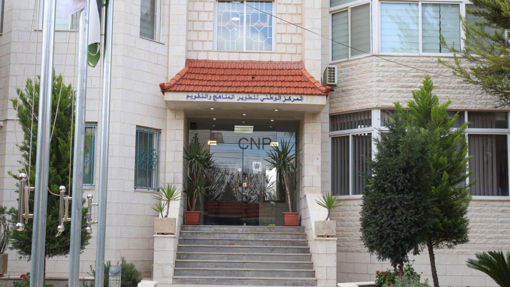 image - Center News Network Beige stone building entrance with red-tiled awning, glass doors labeled 'CNR', concrete steps, and potted plants on either side.