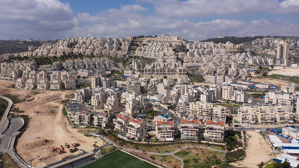 A densely packed hillside neighborhood of beige apartment blocks cascading across terraced slopes under a blue sky