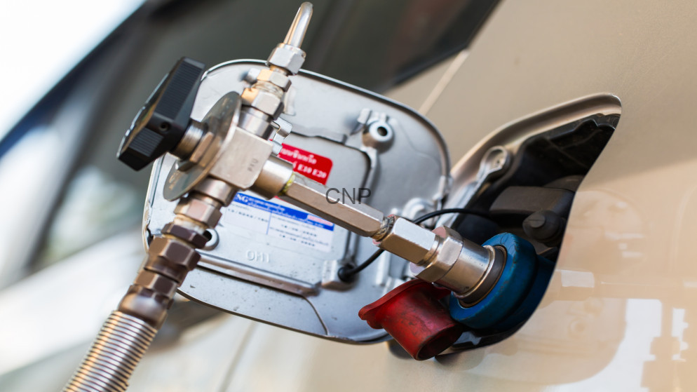 Fuel pump nozzle inserted into a car's fuel filler neck during refueling at a gas station