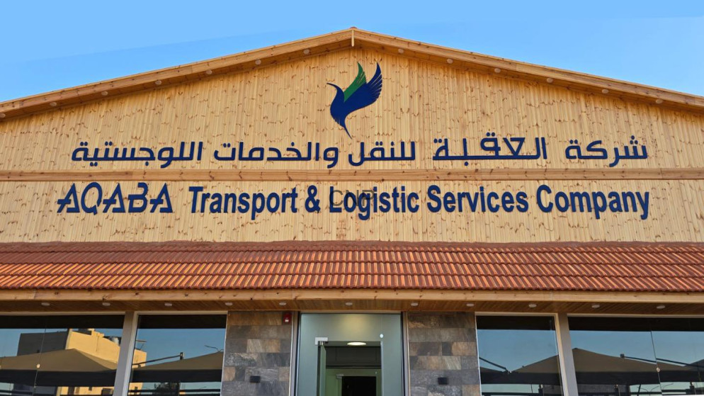 image - Center News Network Facade of a wooden building with a blue logo and bilingual sign reading 'AQABA Transport & Logistic Services Company' (Arabic text above).