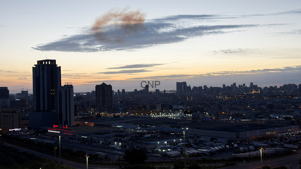 Dusk city skyline with tall buildings and an industrial foreground under a orange-blue sunset.