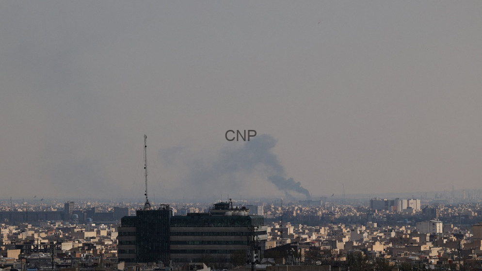 image - Center News Network Urban skyline with a distant plume of smoke rising over the horizon; foreground shows a multi-story building with an antenna.