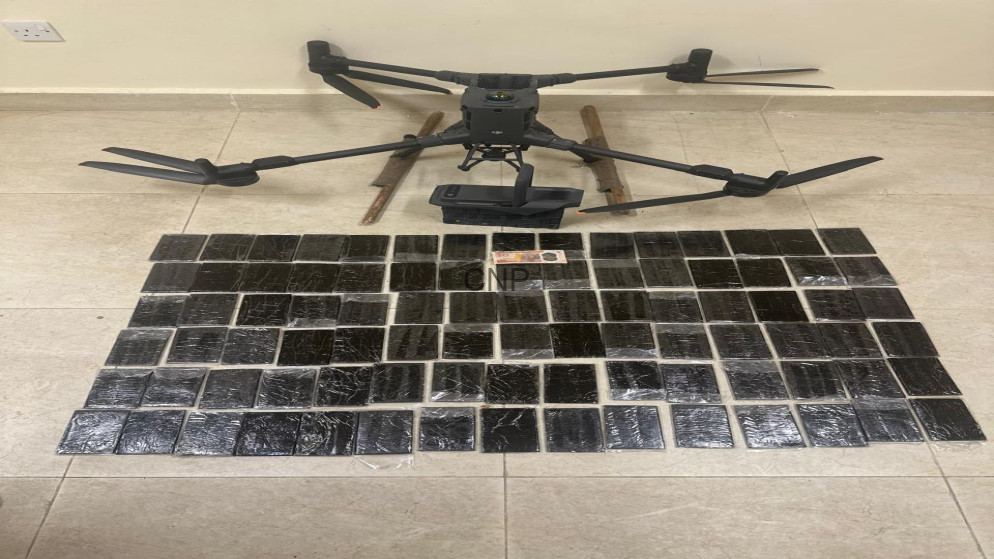 image - Center News Network Quadcopter drone on a tiled floor with a grid of small black solar panels laid out in front of it.