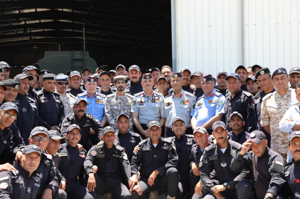 Group of uniformed military personnel posing for a photo in front of a hangar.