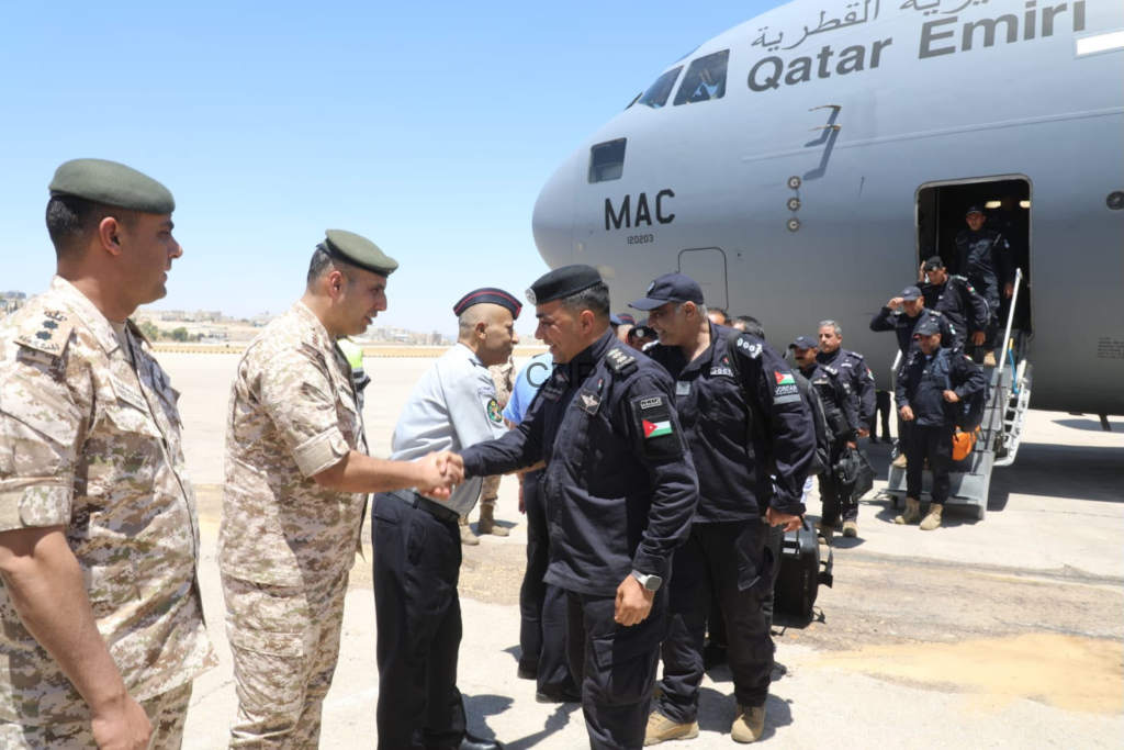 image - Center News Network Military personnel in camouflage and black uniforms shake hands near a Qatar Emiri Airlines aircraft on the tarmac, with crew stepping off the stairs behind them.