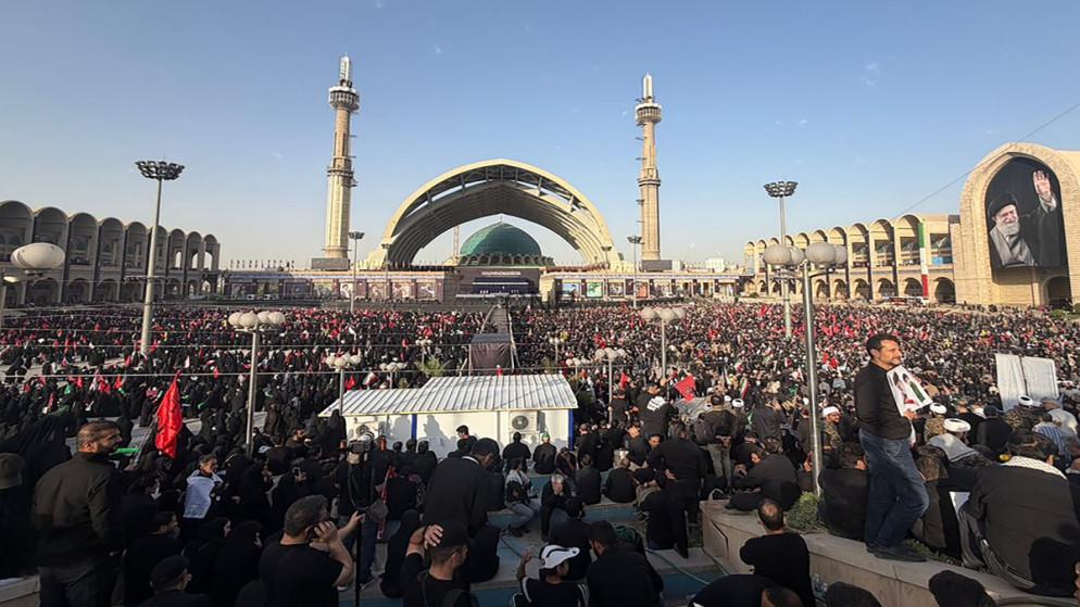 khamni - Center News Network Large crowd gathered at a mosque plaza with a green-domed shrine and tall minarets during a religious event.