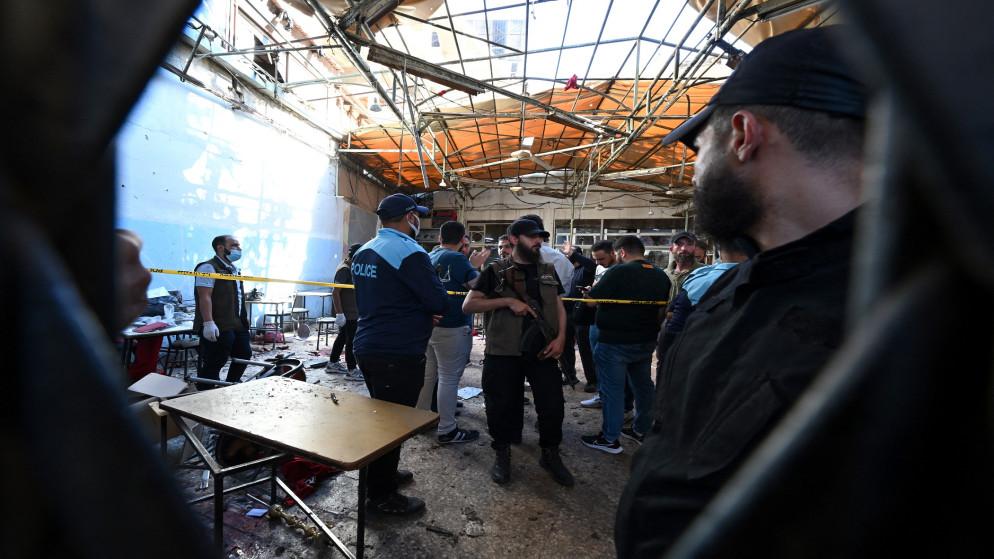 syrm - Center News Network Group of people, including a police officer, in a debris-filled, collapsed building cordoned off with yellow tape.