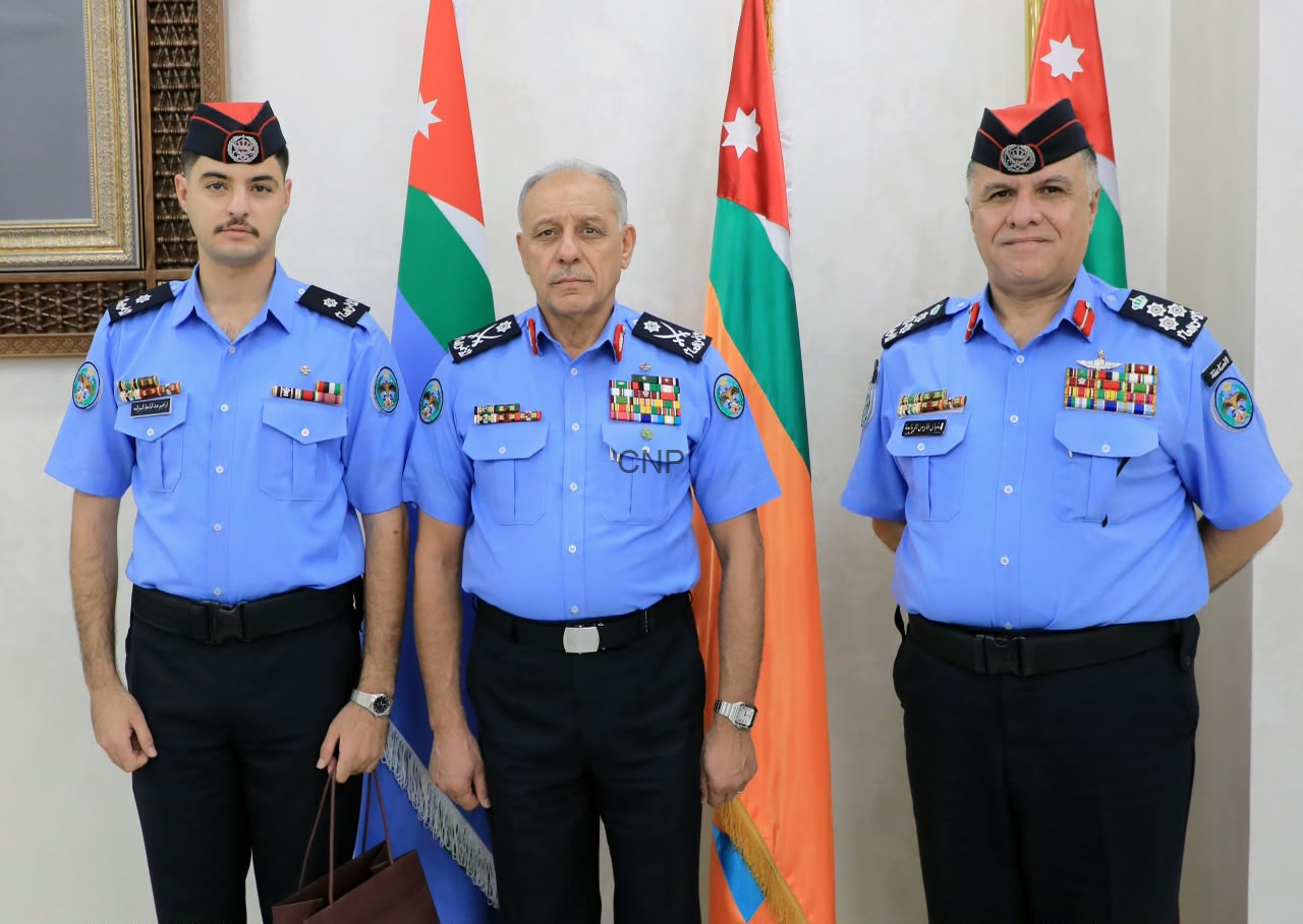 image - Center News Network Three uniformed security officers pose for a formal photo in front of flags, with medals on their chests.