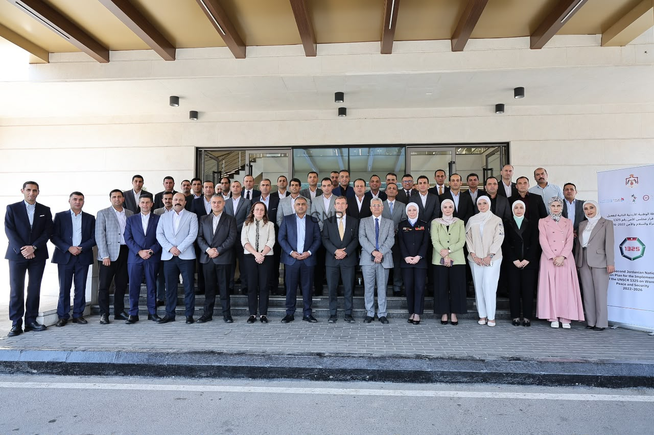 Large group of professionals in formal attire posing on steps outside a building entrance for a group photo. On the right, a banner stands beside the group.