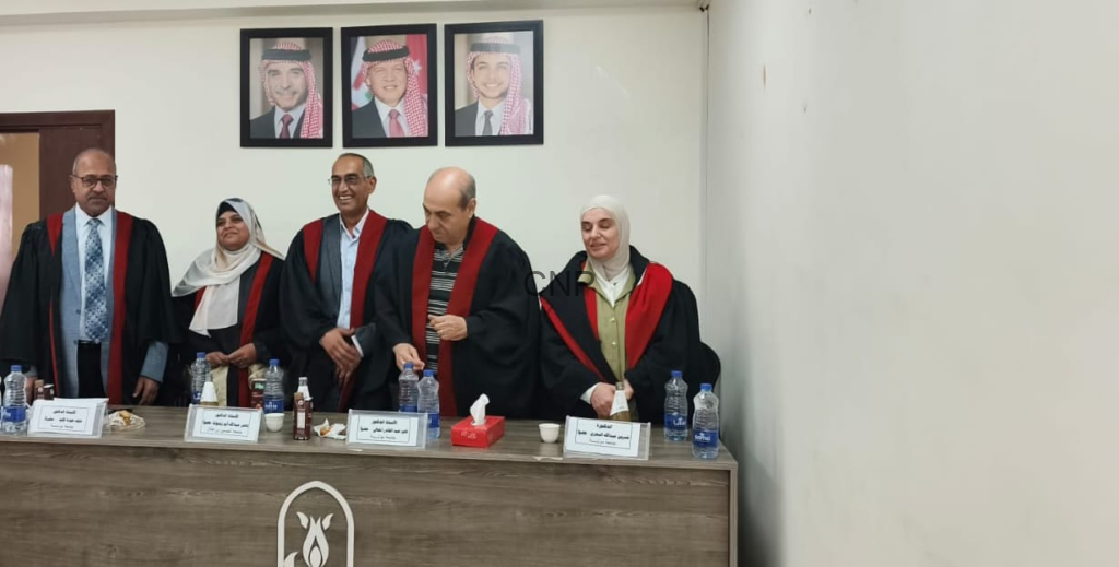 Five academics in black robes with red trim stand behind a conference table during a formal ceremony; portraits hang on the wall behind them.