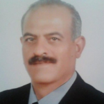 Portrait of a middle-aged man with a mustache, wearing a dark suit and light shirt, looking at the camera.