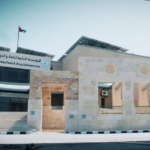 Exterior view of a government building labeled Jordan Food & Drug Administration, with steps leading up and a Jordan flag nearby on the left.