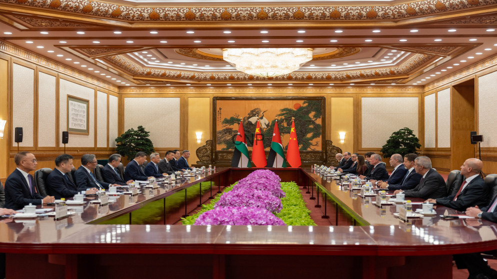 image - Center News Network Diplomatic meeting in a grand boardroom with two long desks facing each other and flags at the center, surrounded by officials.