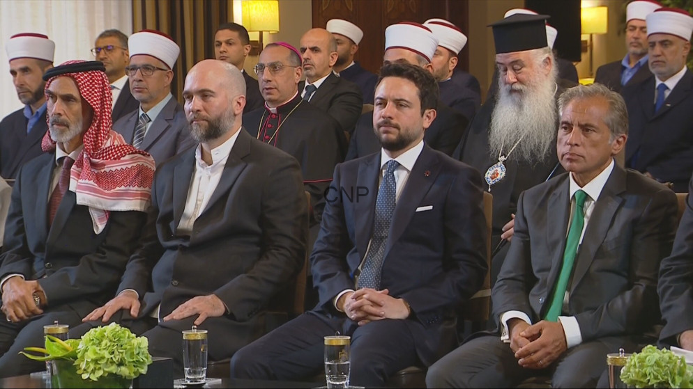 image - Center News Network Group of men in suits and traditional religious attire seated at a formal event, facing forward.