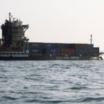 Container ship sailing on calm ocean with stacked colorful cargo containers on deck