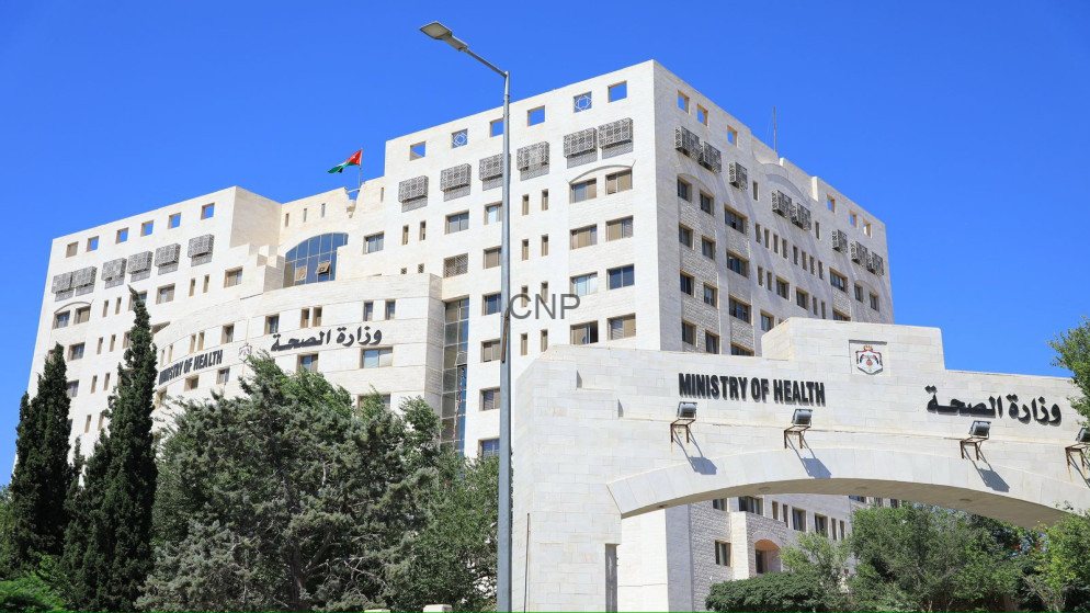 White stone Ministry of Health building with an arched entrance, palm trees, and a bright blue sky; appears to be a government health complex.