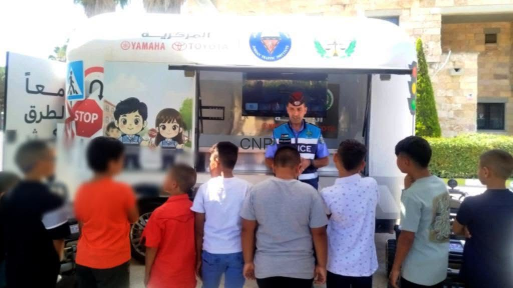 image - Center News Network Police officer in a mobile outreach van addressing a group of children outdoors.