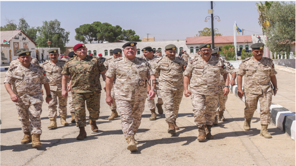 A squad of soldiers in desert camouflage uniforms marching toward the camera on a sunny day.