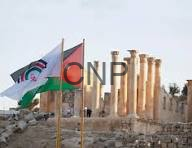 Flags flutter in front of ancient ruin with tall stone columns under a clear sky.