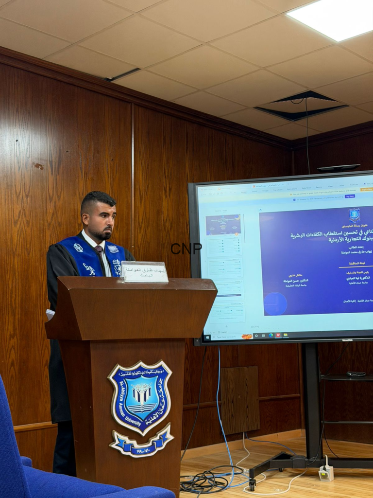 image - Center News Network Man in academic gown and blue sash stands at a wooden podium with a university crest, presenting.