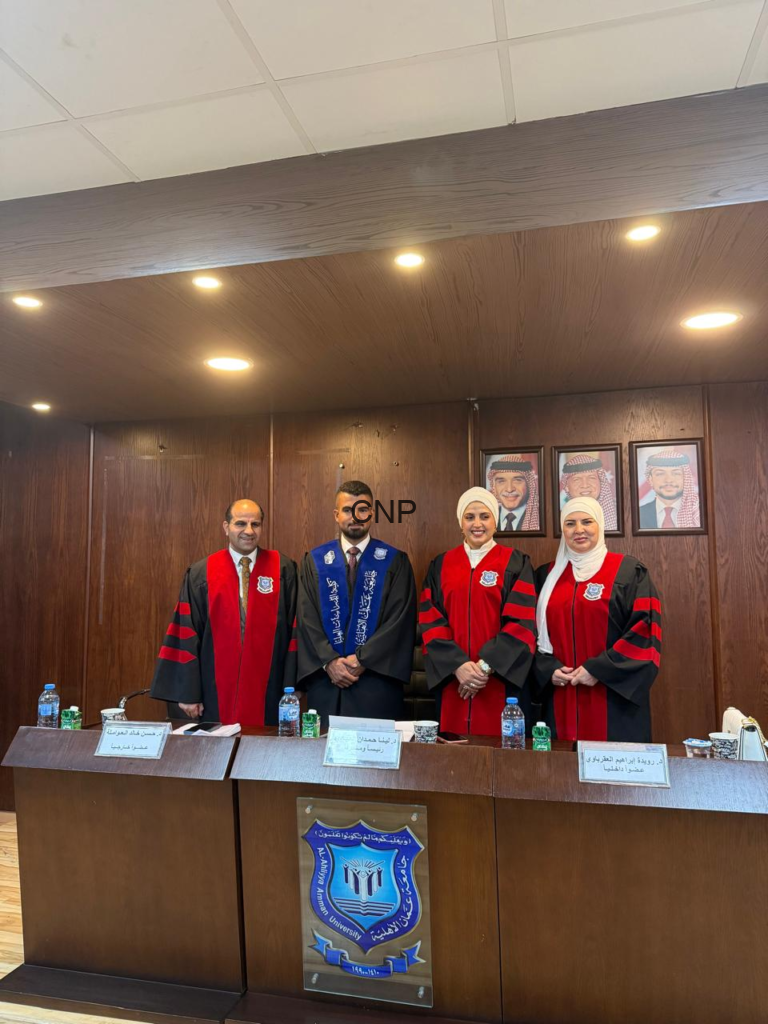 image - Center News Network Four academics in red-and-black robes stand behind a wooden panel at a formal ceremony, with framed portraits on the wall behind them and a university crest on the front panel.